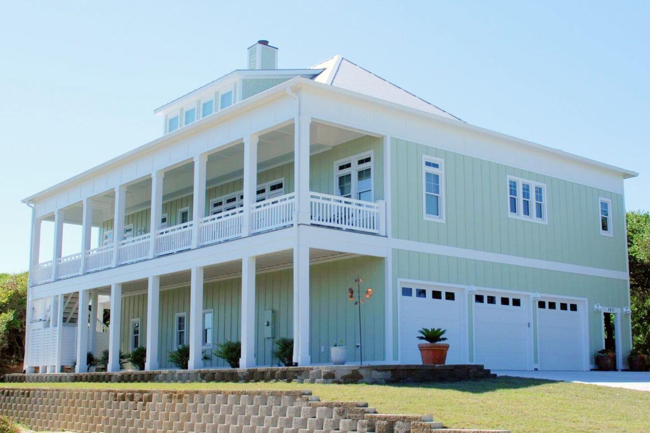 Image of 2 story house, mint green & 3 garage doors.