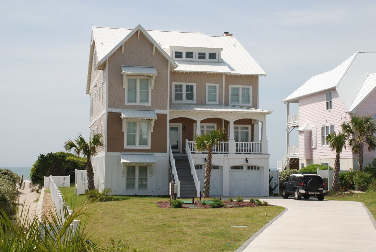 Photo of 3 story house, 2 car garage, steep stair case, jeep in driveway, and pink house next door.