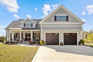 Front view of house, with peaked roofs, double car garage and blue skies.