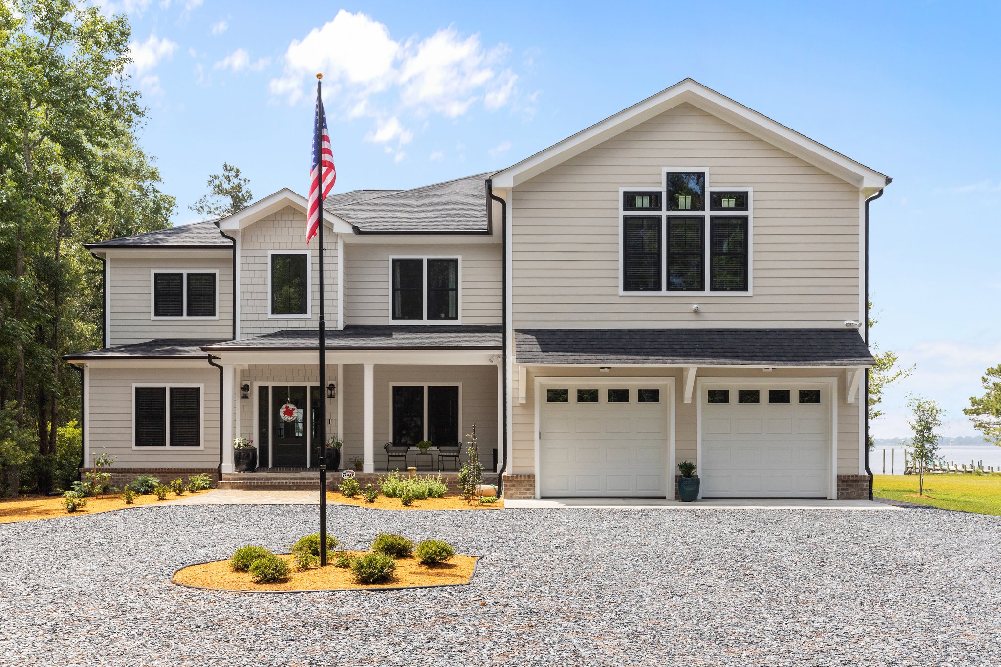Photo of front view of home with 2 car garage and American flag in round about driveway.