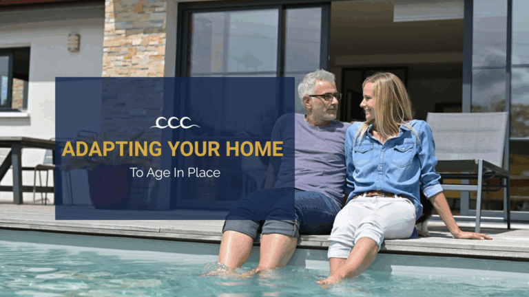 Older couple sitting by their backyard pool outside a modern coastal home, representing aging in place renovations by Crystal Coast Construction.